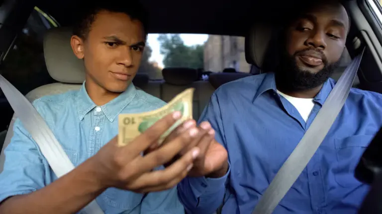 Dad behind wheel hands passenger son $10 bill