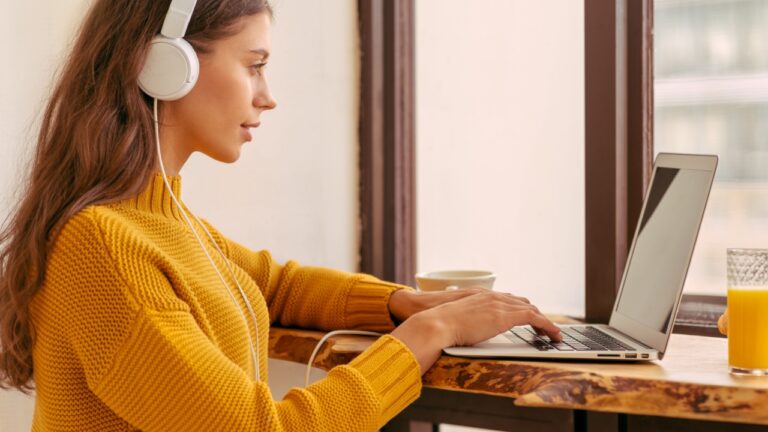 Nice beautiful female with blonde long hair working on laptop sitting at home