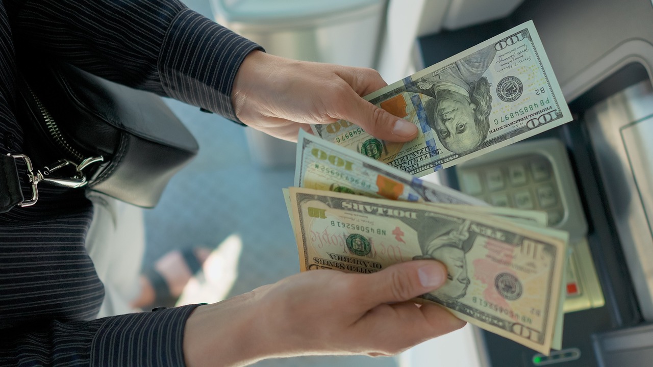 Business woman counting us dollars near ATM machine