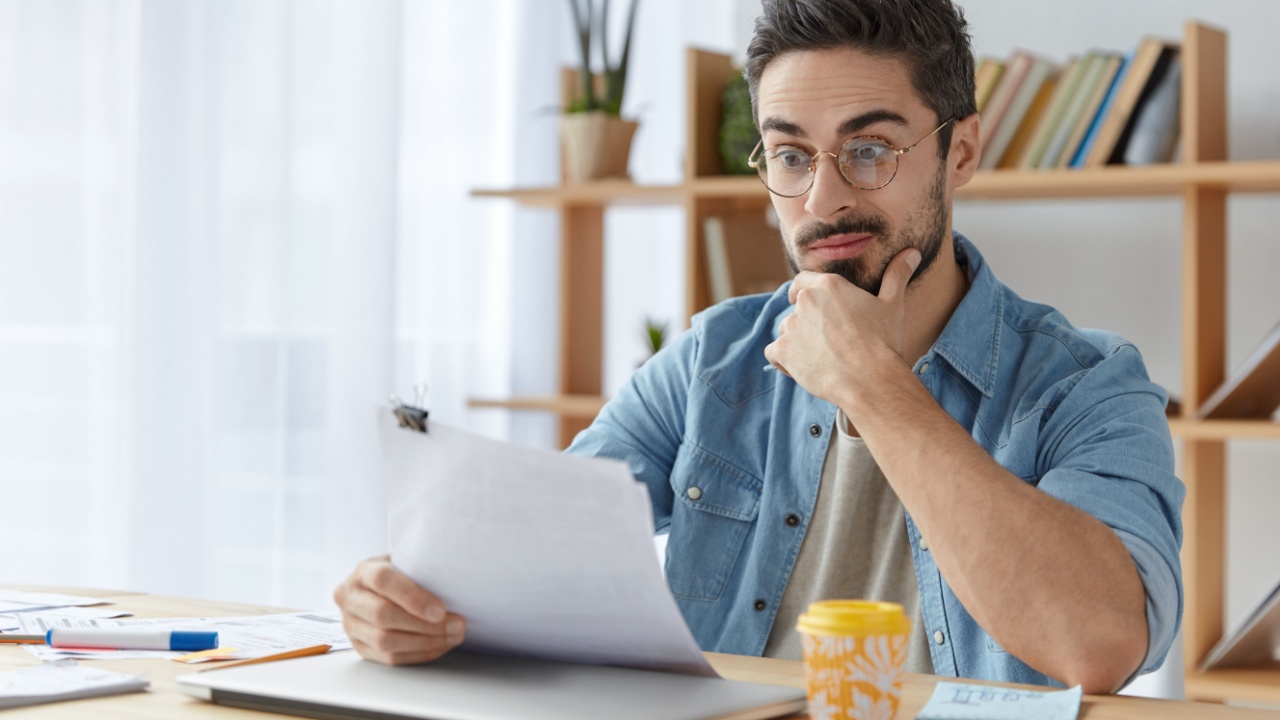 man looking at paperwork confused in home office