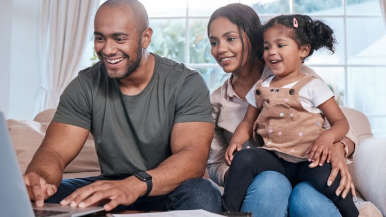 young couple and daughter using laptop at home