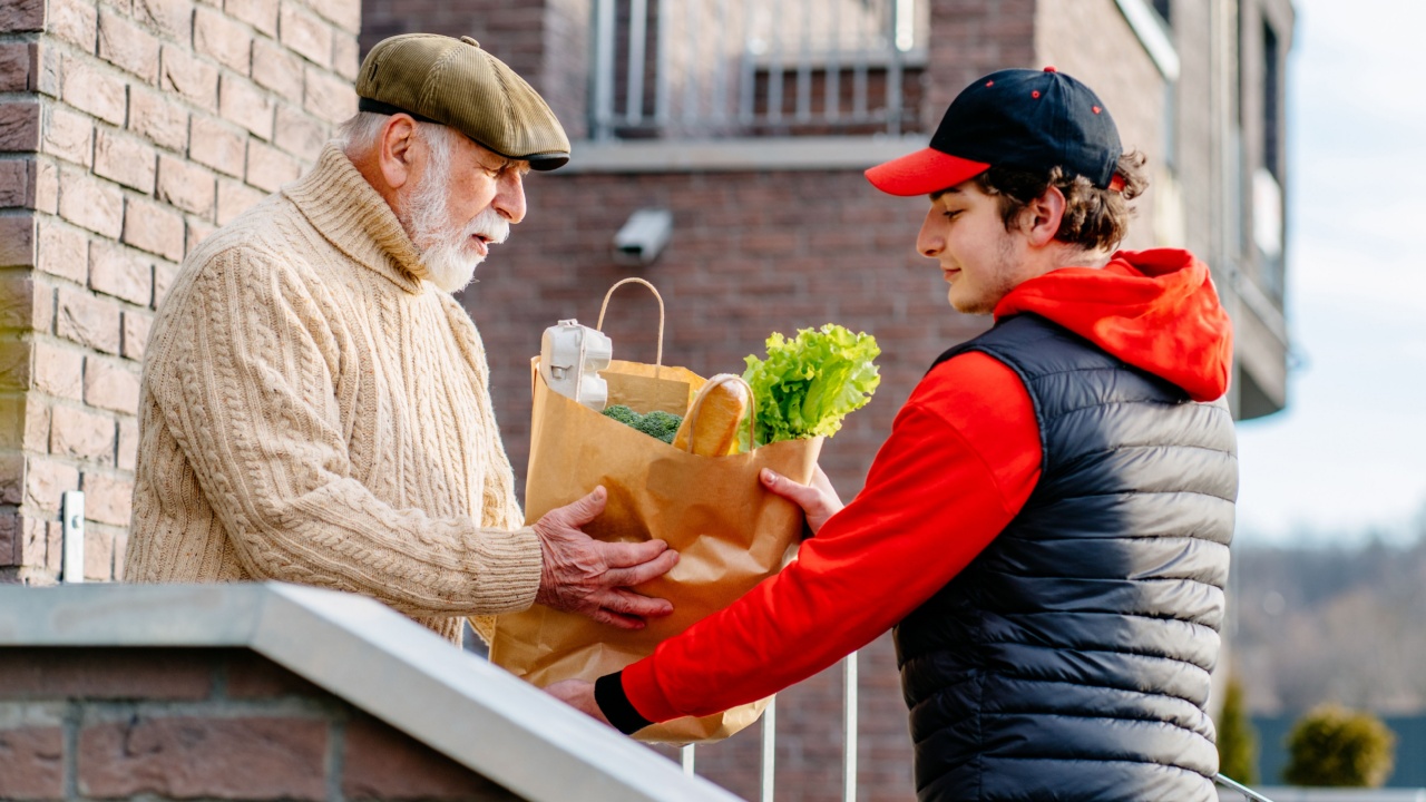 young man delivering groceries to older man at home