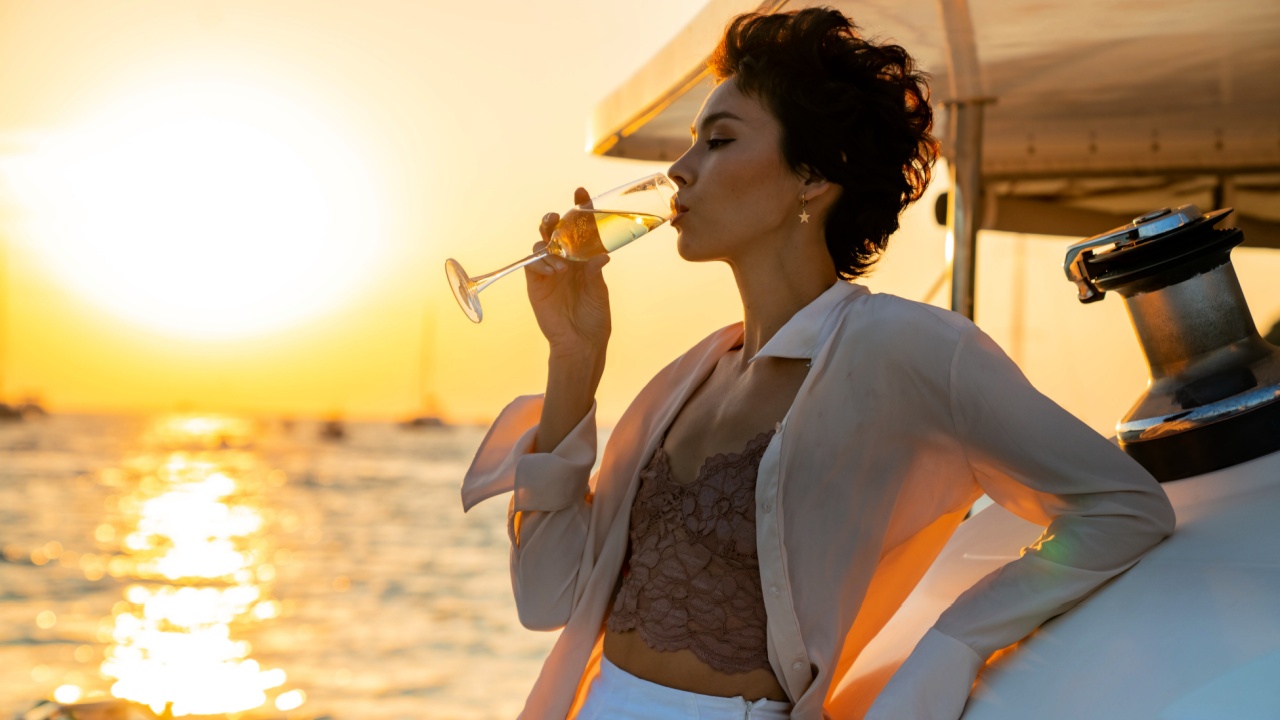 woman enjoy outdoor luxury lifestyle with drinking champagne while catamaran boat sailing at summer sunset