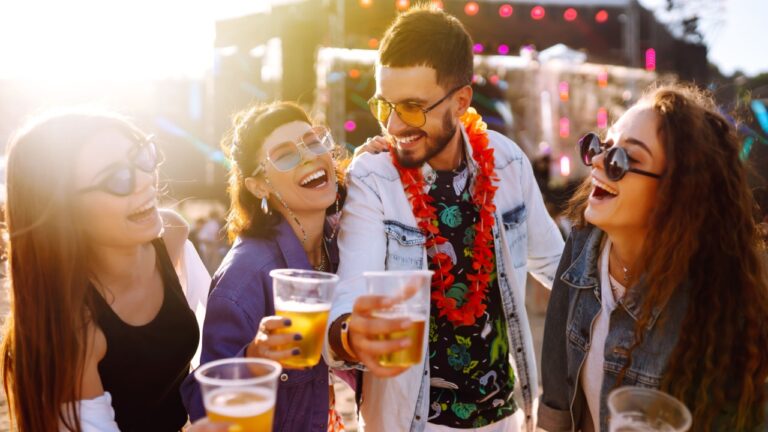 Young happy friends drinking beer and having fun at music festival together