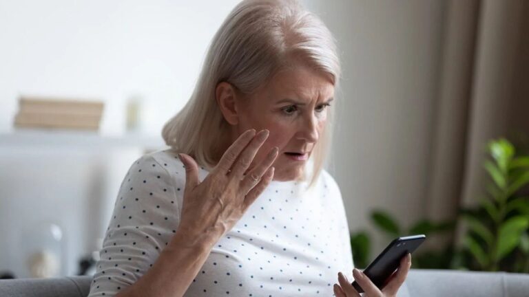 An older woman looking shocked at her phone.