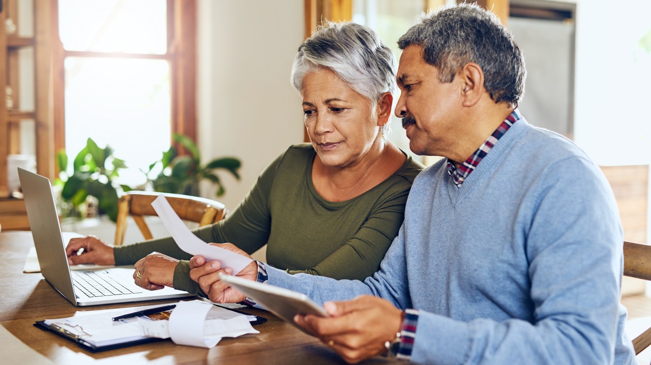 Senior couple, budget planning and health insurance checklist with computer at home.